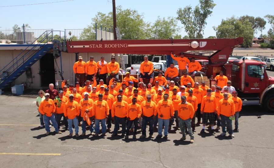 The Star Roofing crew in orange company shirts in front of a Star Roofing truck